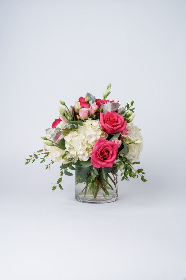 Bright pink and blush roses with white hydrangeas in clear glass vase floral arrangement