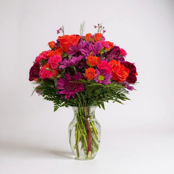 Vibrant bouquet of red, orange, and purple flowers in a glass vase – Quinn Florist