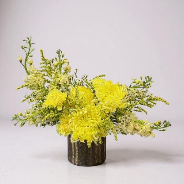 Modern yellow flower arrangement in a low black ceramic vase with mums and delicate filler flowers