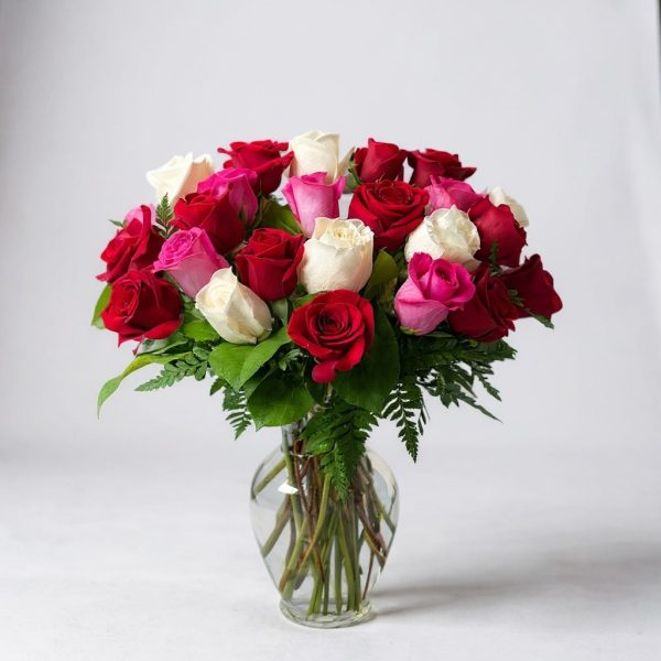 Red, white, and pink rose arrangement in clear glass vase